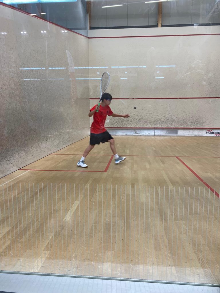 Un junior en maillot rouge frappe la balle pendant un match