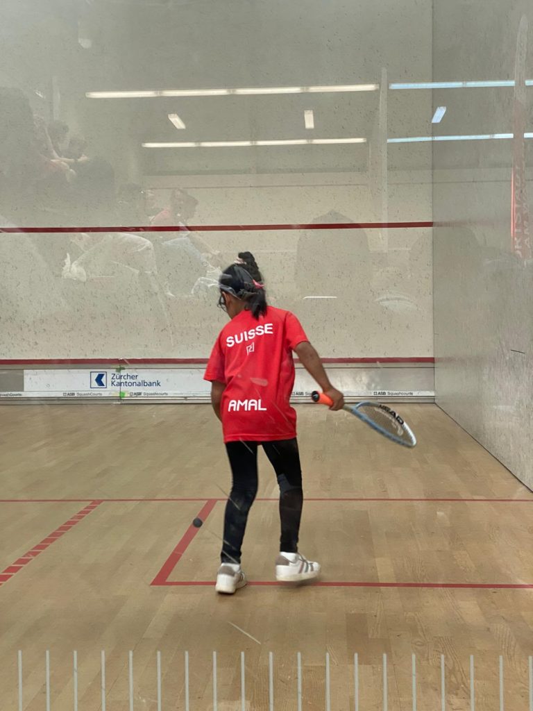 Amal Zafar, en maillot rouge de l'équipe de Suisse, en position sur le court